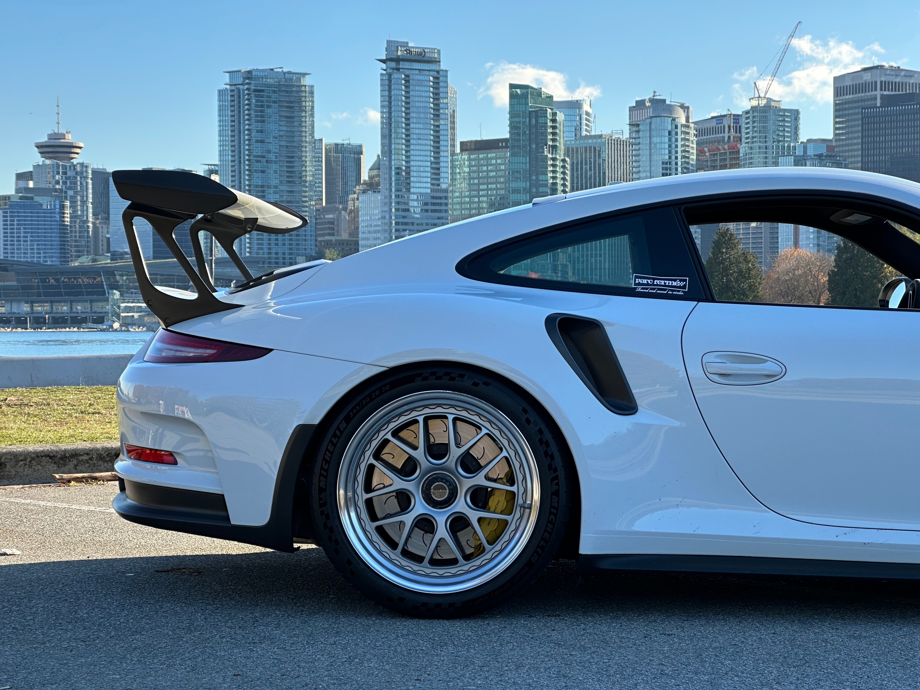 Silver Porsche 911 outside a modern home overlooking a misty mountain lake